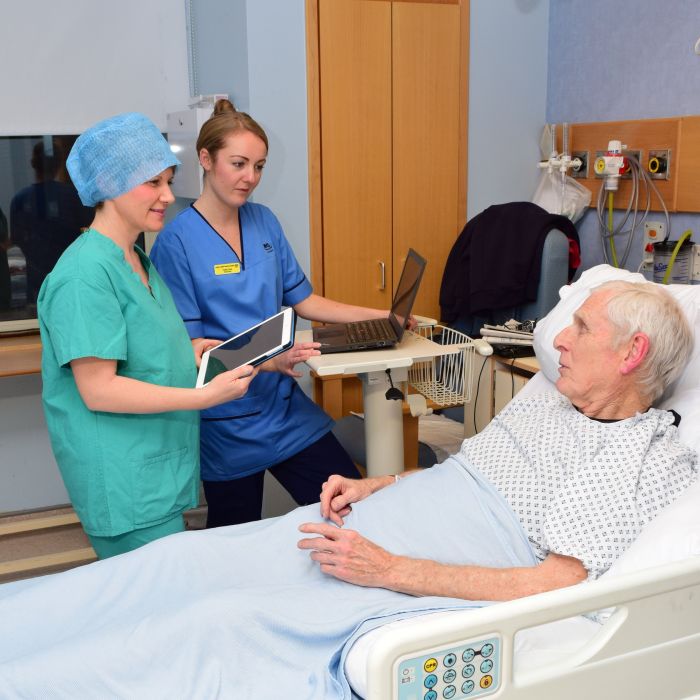 nurses with patient at hospital bed