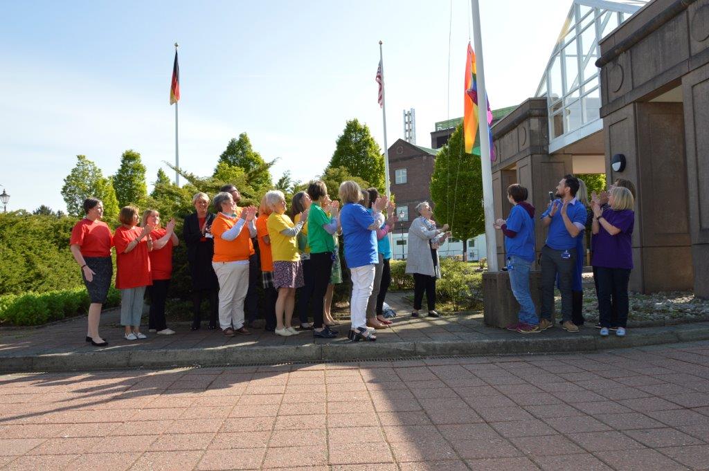 LGBT flag raising. group in brightly cooured tshirts.