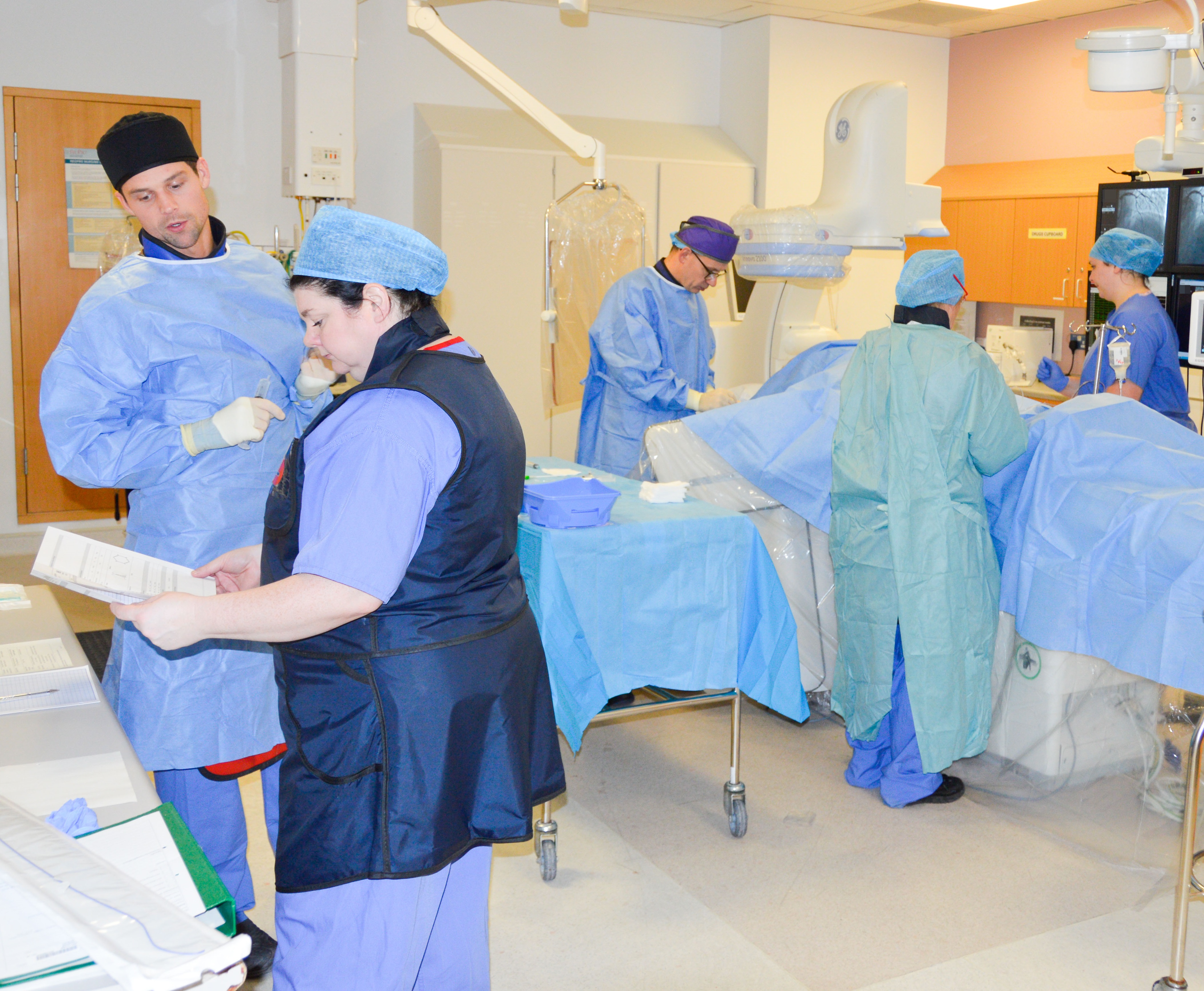 Theatre staff work on patients in cath lab.