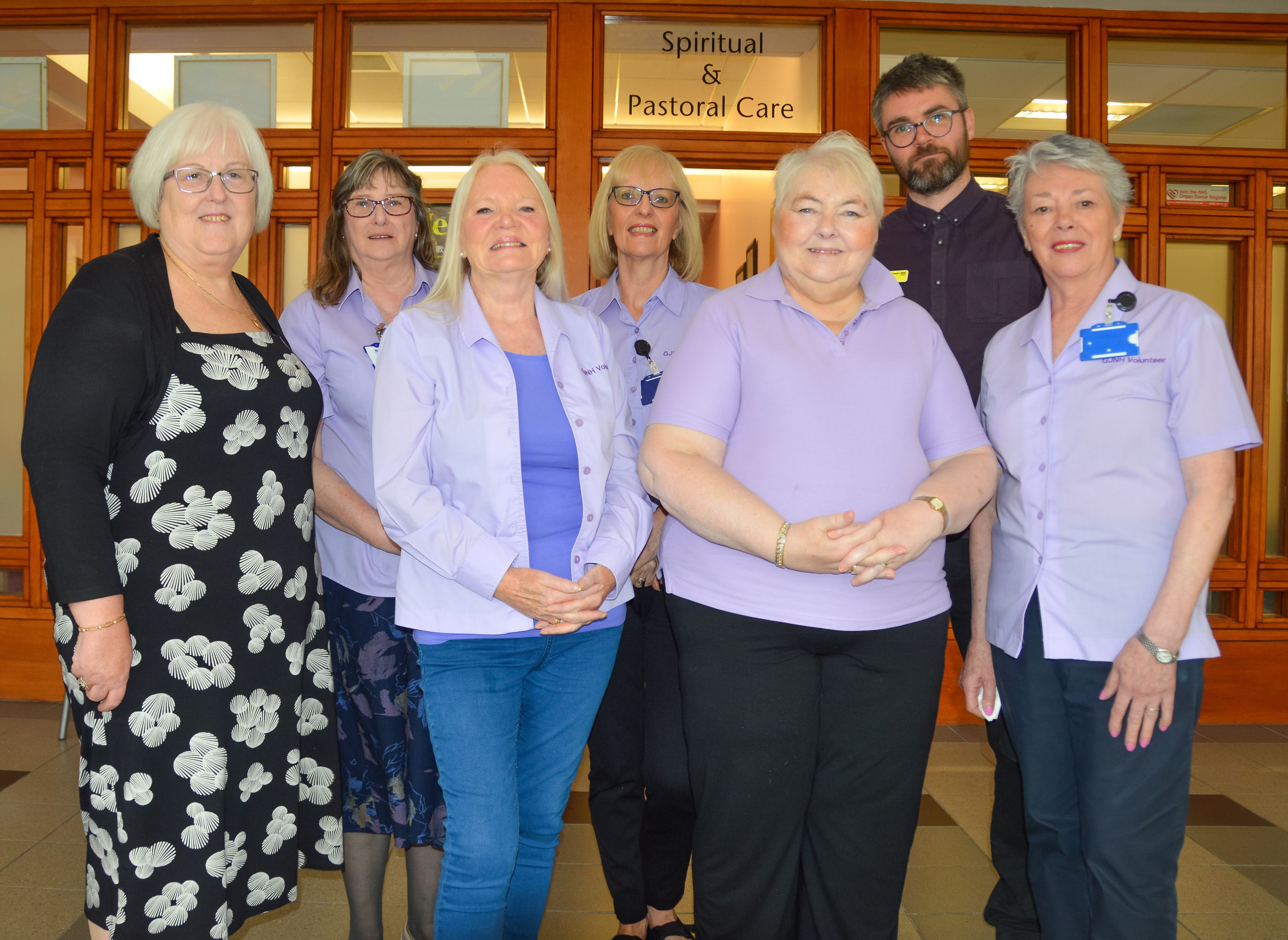 Pastoral care volunteers standing smiling outside of Spiritual Care office.