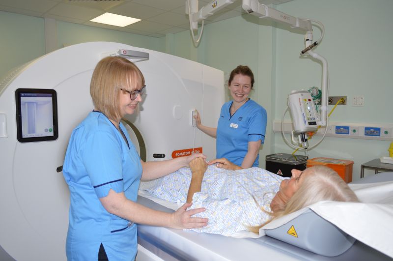 two nurses with patient going into scanner