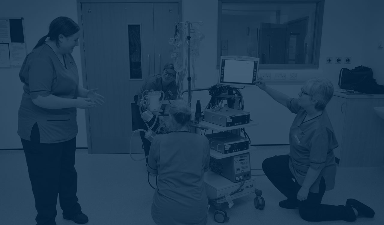 Four nurses gather around clinical devices. 
