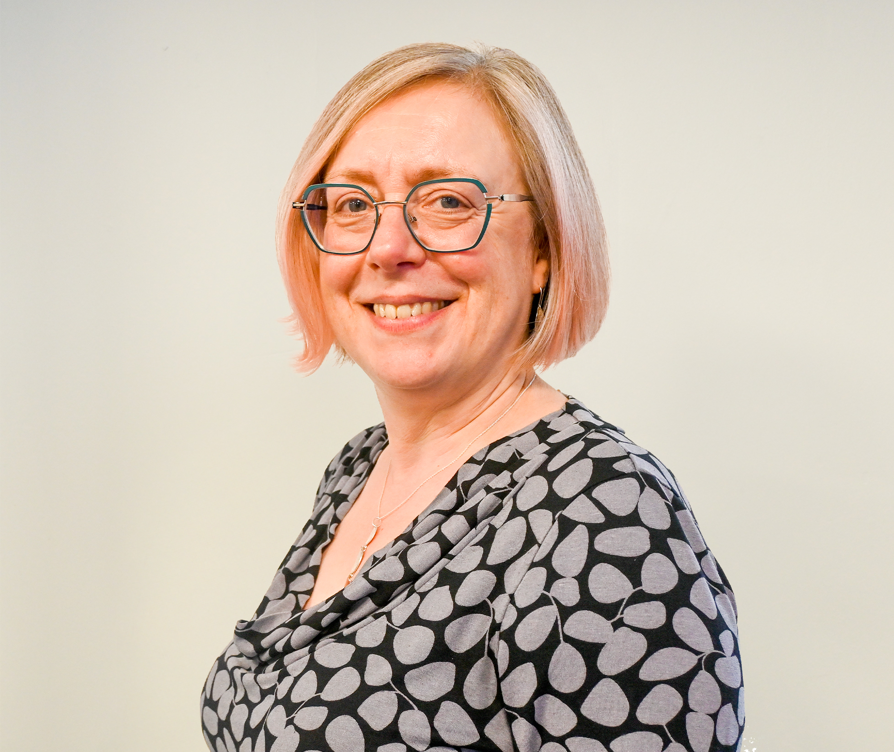 Rebecca smiling for headshot, wearing glasses.
