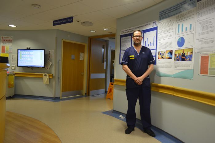 Man standing in ward corridor and smiling.
