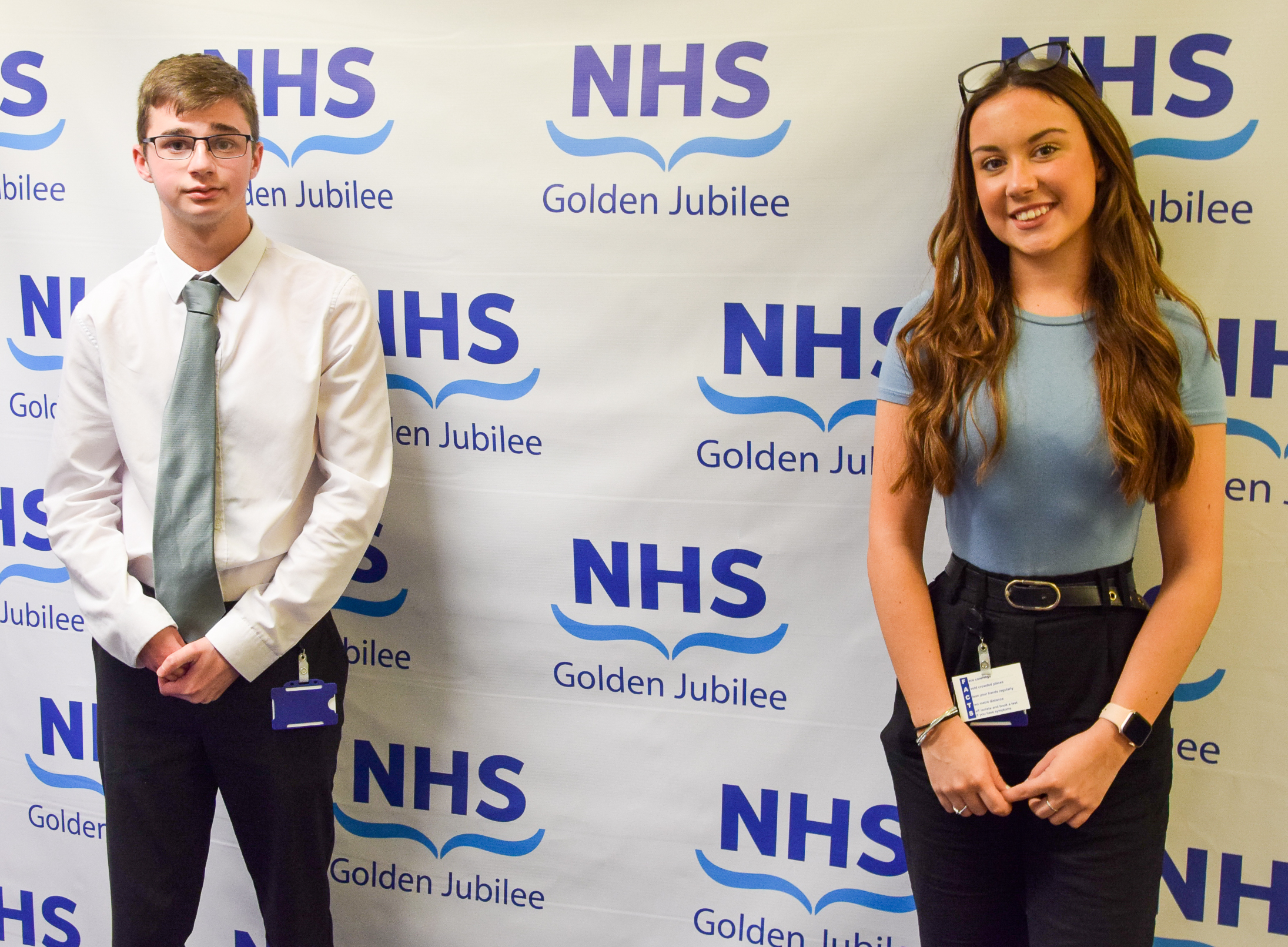 Robert Lamont on the left and Megan Collier on the right standing next to NHS Golden Jubilee backdrop.