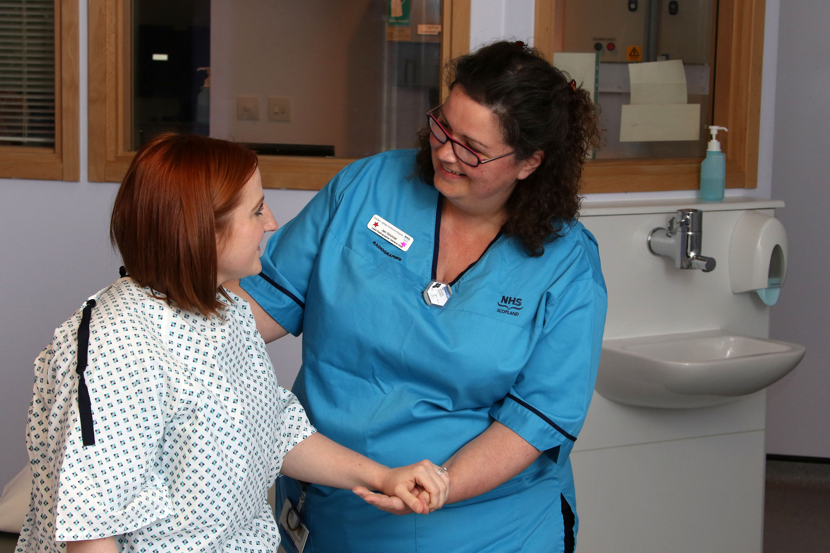 Female nurse assisting patient and holding her hand. 