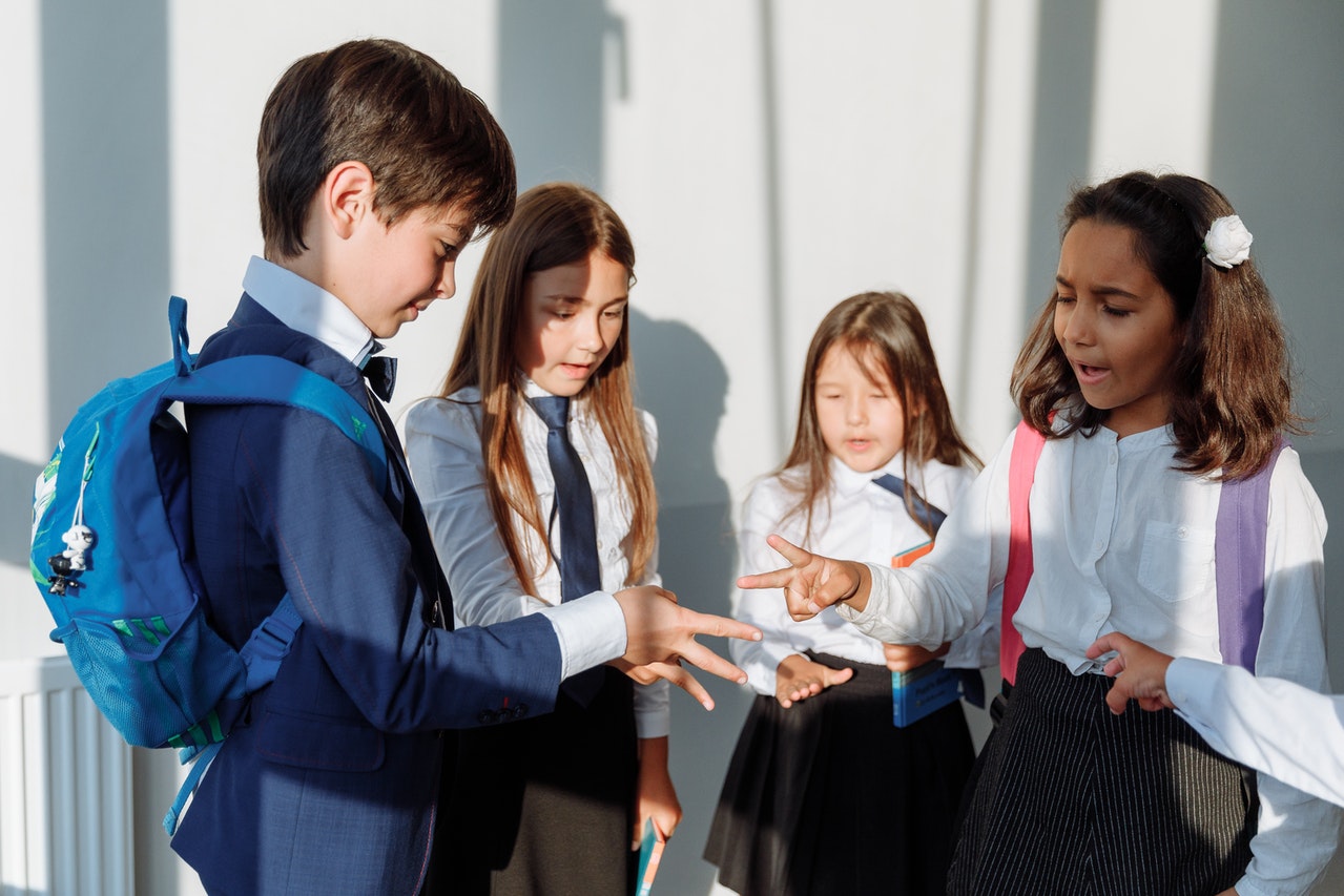 Children in school uniform playing rock, paper, scissors. 