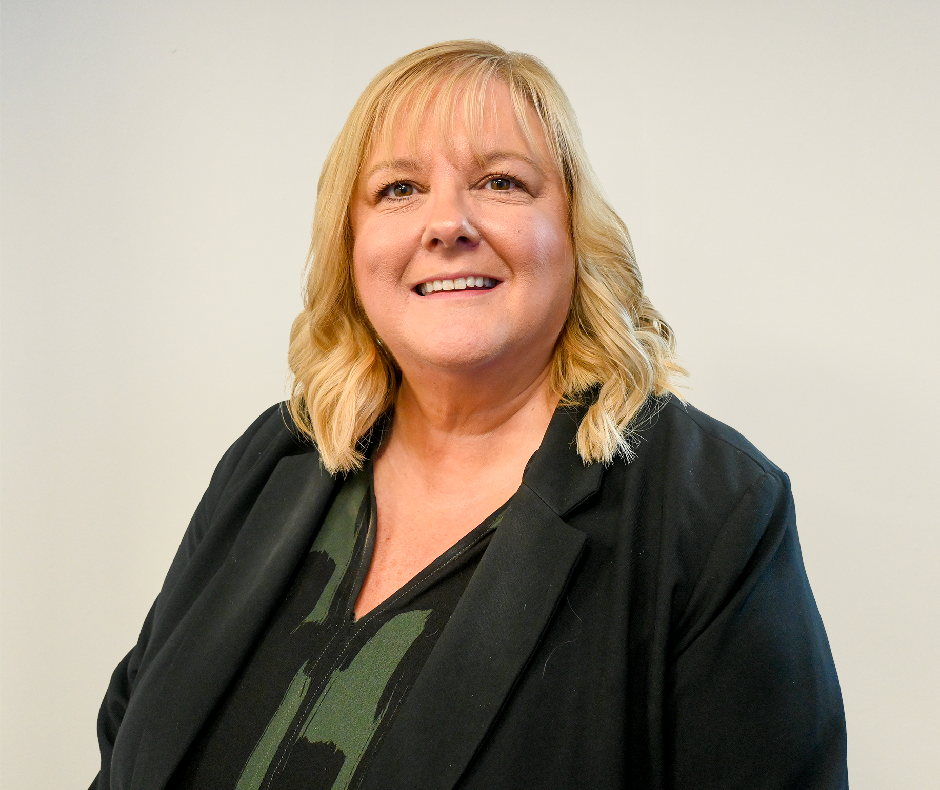 Carlynne O'Conner smiling with black blazer and NHS lanyard on.